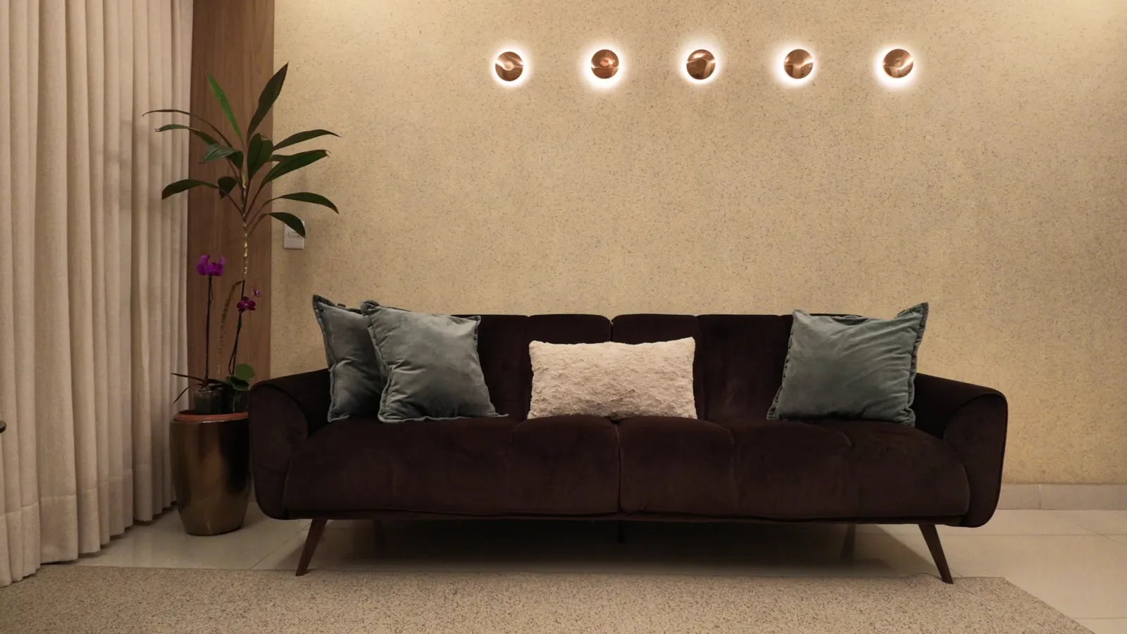 Sala de atendimento com sofá, almofadas e luminárias de parede